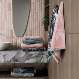 Stack of patterned towels on marble countertop with two hanging towels beside