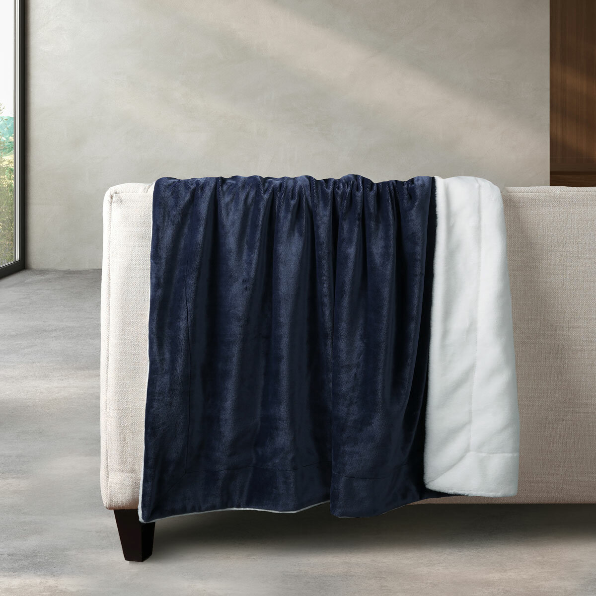Navy and white plush throw draped over a neutral-toned couch