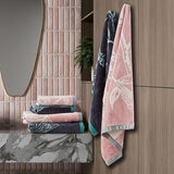 Folded and hanging towels in pink, grey, and blue with bird design