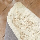 Folded beige faux fur rug with thick, fluffy texture on wooden floor