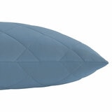 Quilted light blue body pillow with diamond stitching placed in front of two white pillows on a neatly Quilted light blue body pillow with diamond stitching placed in front of two white pillows on a neatly