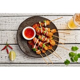 Chicken Satay sticks laid out on a plate with garnish