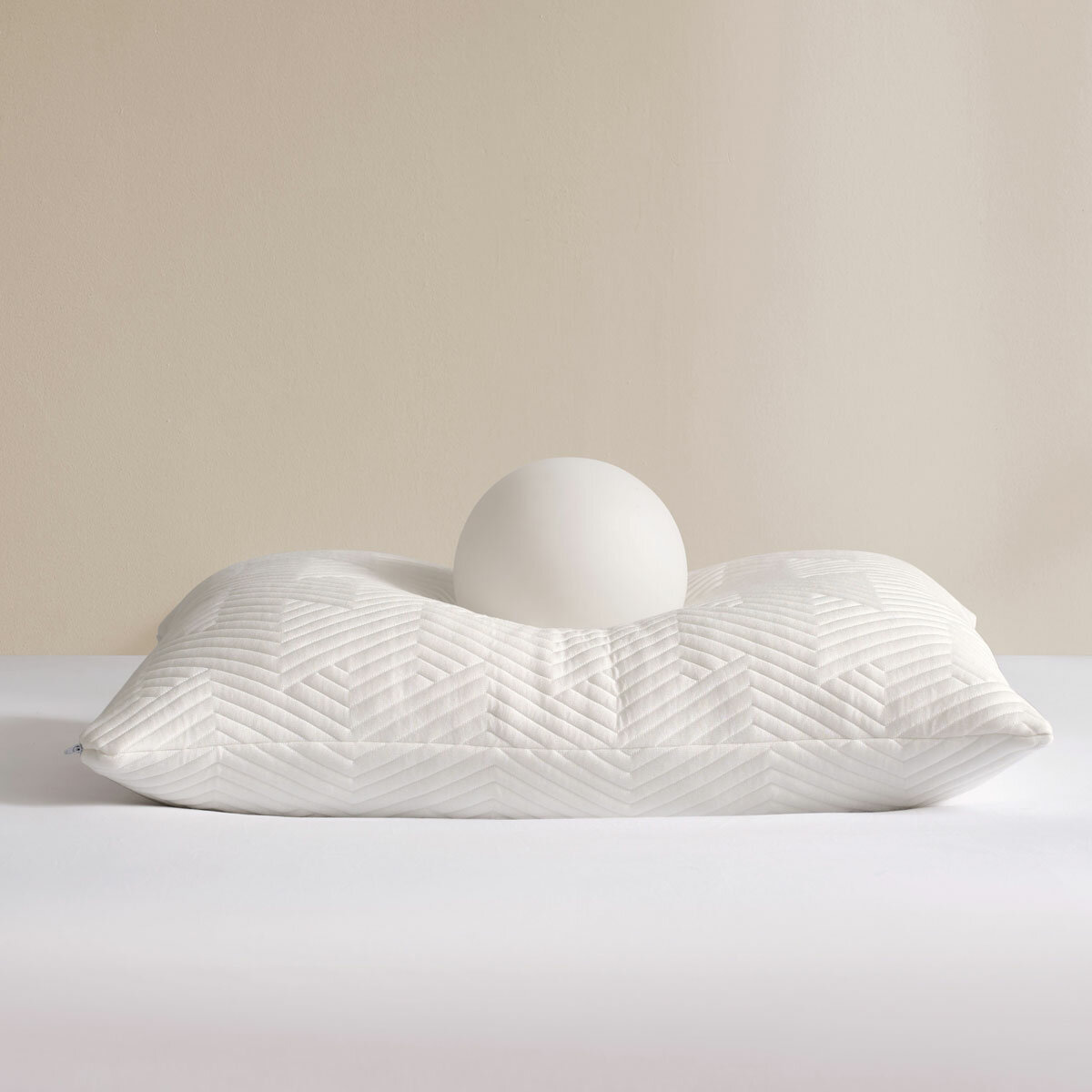 White pillow, showcasing firmness and softeness with a white balll placed on top
