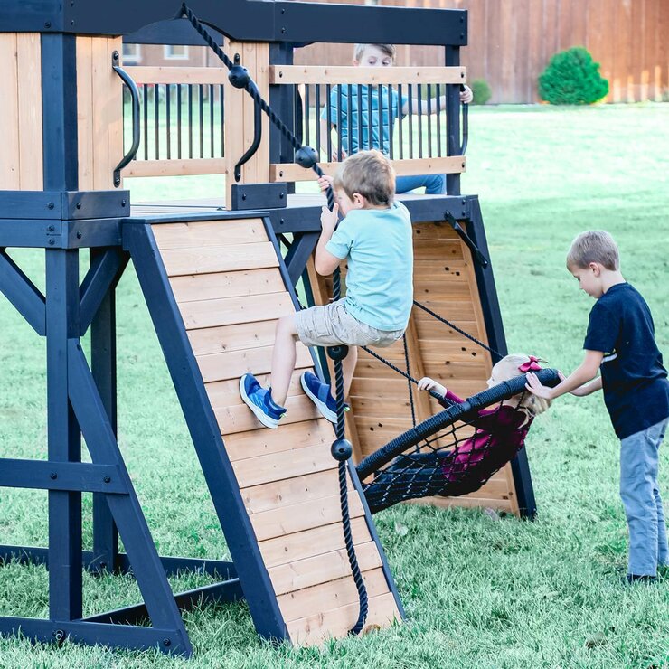Lifestyle image of a child climbing the wall, and two children using the web swing