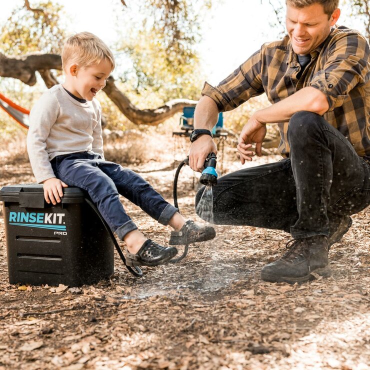 Lifestyle image showing a man washing a child's feet with the Rinsekit Pro