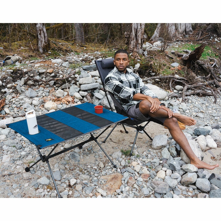 Lifestyle image of a man sat next to the table which has drinks in the cup holders