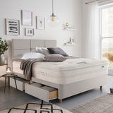 Lifestyle image of made up bed in dove grey in front of window showing beachside