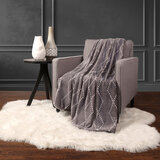 Lifestyle image of grey geo printed plush throw over sofa