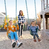 Lifestyle image of a woman pushing two children on the swings Lifestyle image of a woman pushing two children on the swings