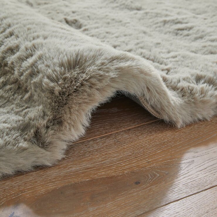 taupe faux fur rug with thick, fluffy texture on wooden floor taupe faux fur rug with thick, fluffy texture on wooden floor