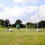 Lifestyle image of a child kicking balls into the goal