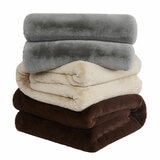 Stack of three plush throws in grey, beige and dark brown