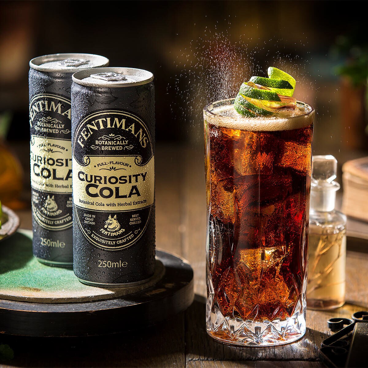 Image of 2 cans of fentimans cola in a dark setting