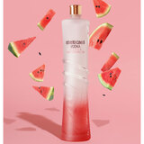 Lifestyle image of bottle in front of pink background with watermelons