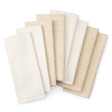 Eight folded neutral-toned towels with subtle woven patterns, arranged in a fan to show variety