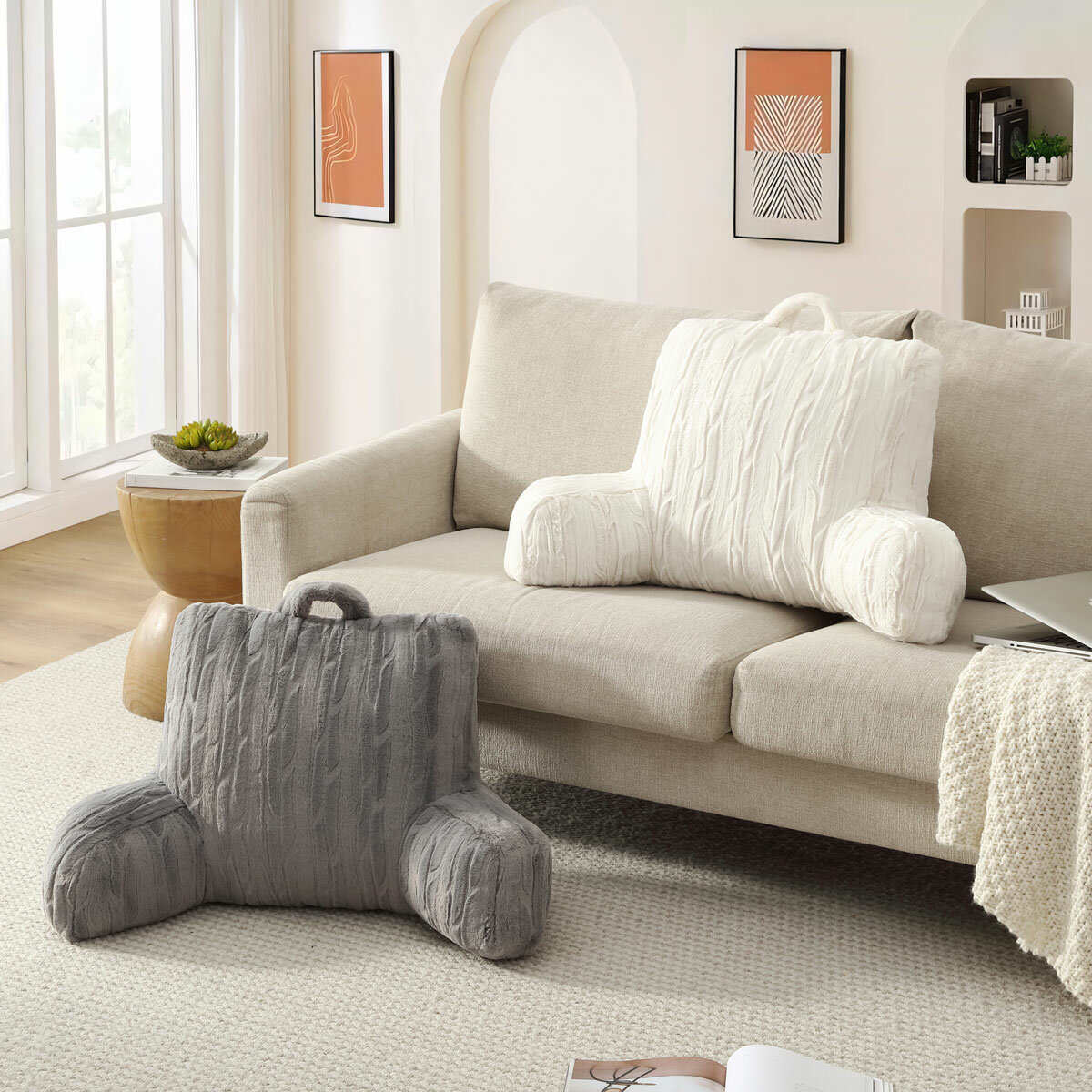 Embossed faux fur bed rest pillow in cream and grey, in a lifestyle image on sofa and floor.