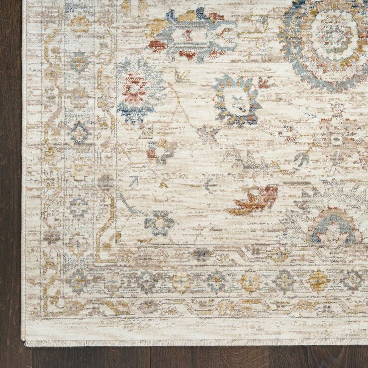 Beige rug with symmetrical floral and geometric pattern in muted blue, red, yellow, and grey