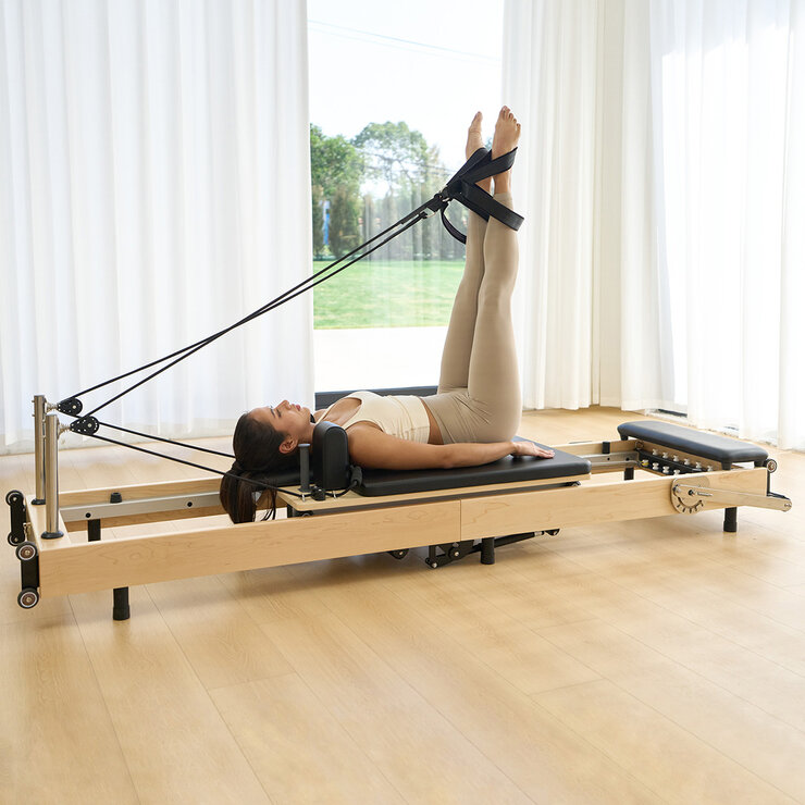 Lifestyle image of a woman using the reformer Lifestyle image of a woman using the reformer