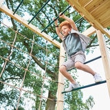 Lifestyle image of a child using the monkey bars Lifestyle image of a child using the monkey bars