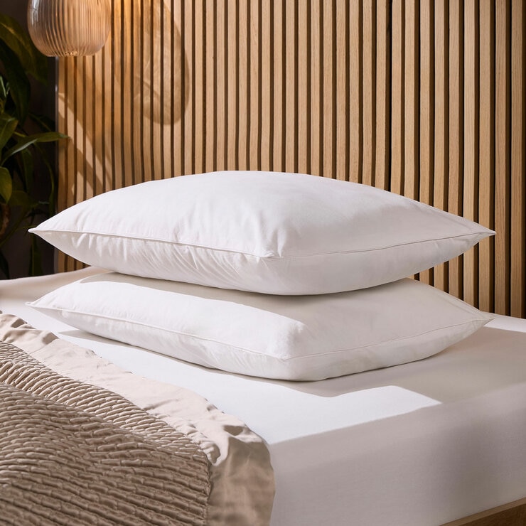 Two white pillows against a wooden headboard