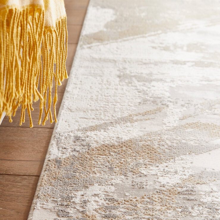 Close-up of a plush abstract rug in beige, grey and white with raised, distressed-style texture.