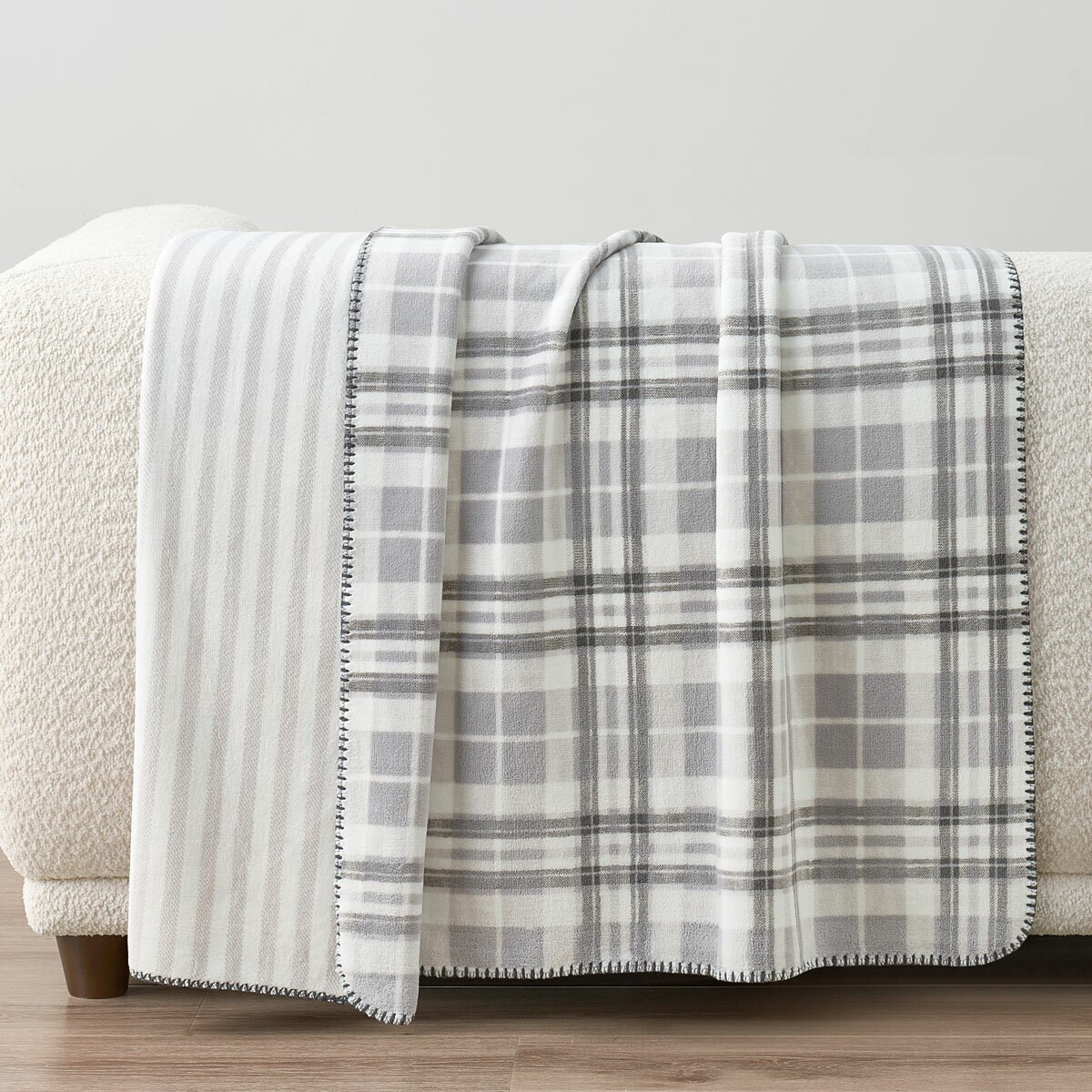 Grey floral throw staged on white sofa in a lifestyle image