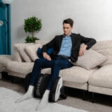 Lifestyle image of model usingt the massager on their calves in living room