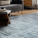 Large striped rug in blue, grey and white on wooden floor, styled with modern living room furniture.