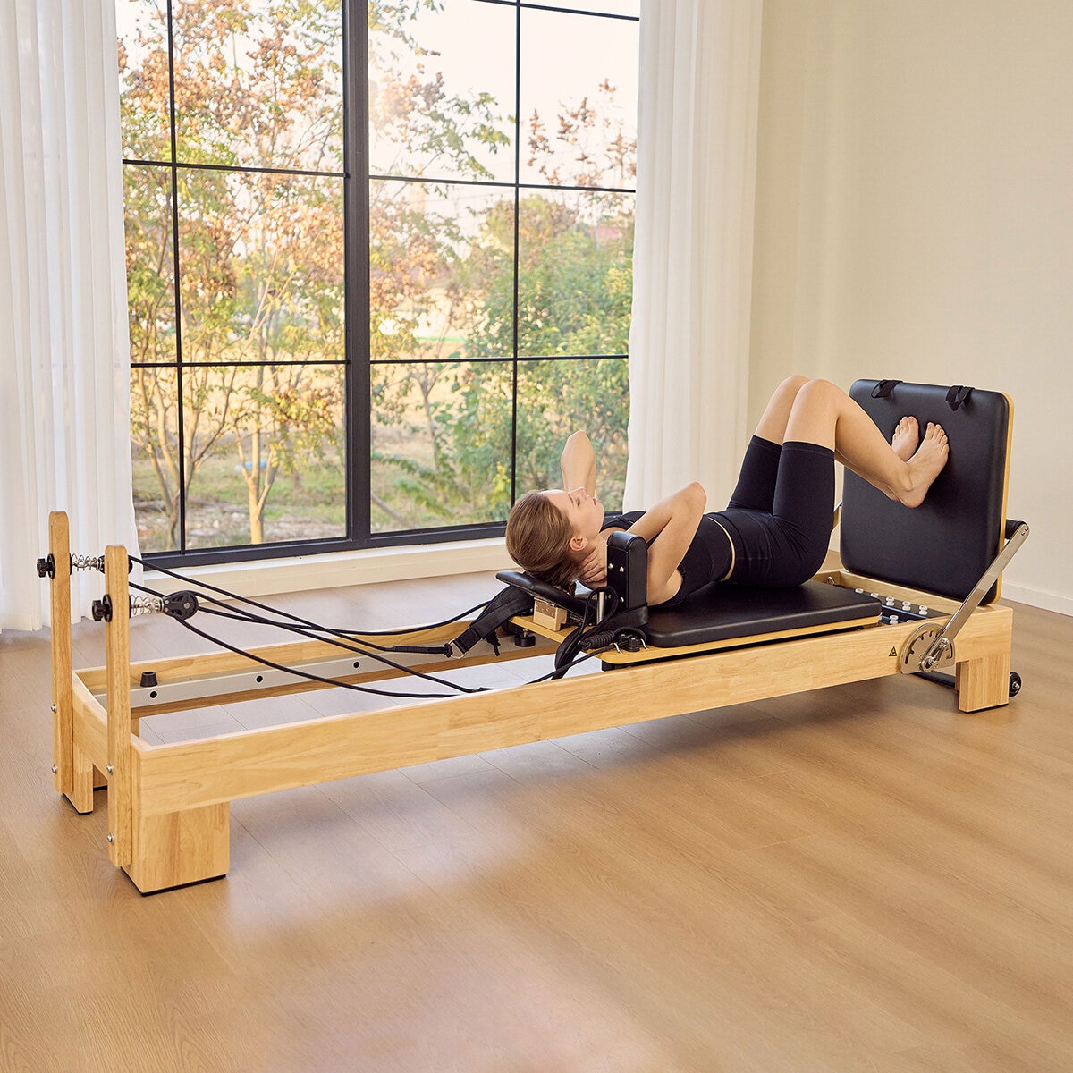 Lifestyle image of a woman using the reformer Lifestyle image of a woman using the reformer