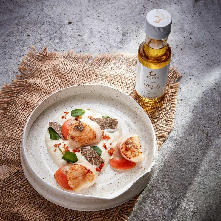 Truffle Hunter White Truffle Oil next to plate of food Truffle Hunter White Truffle Oil next to plate of food