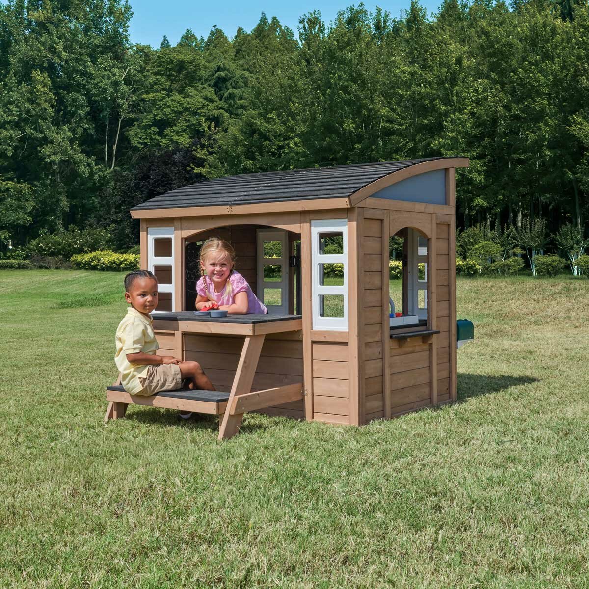 Lifestyle image of a child sat at the picnic area and another child in the playhouse Lifestyle image of a child sat at the picnic area and another child in the playhouse