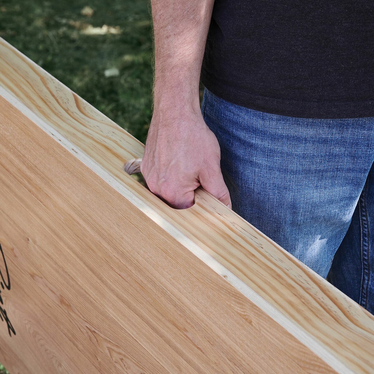 Lifestyle image showing someone using the carry handle to carry the Cornhole