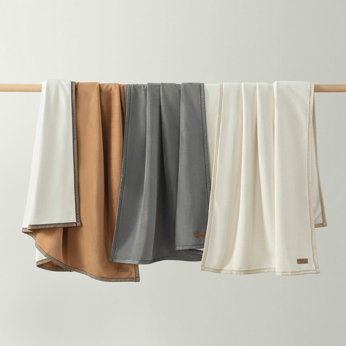 Ivory, camel and grey throw hung on a wooden bar