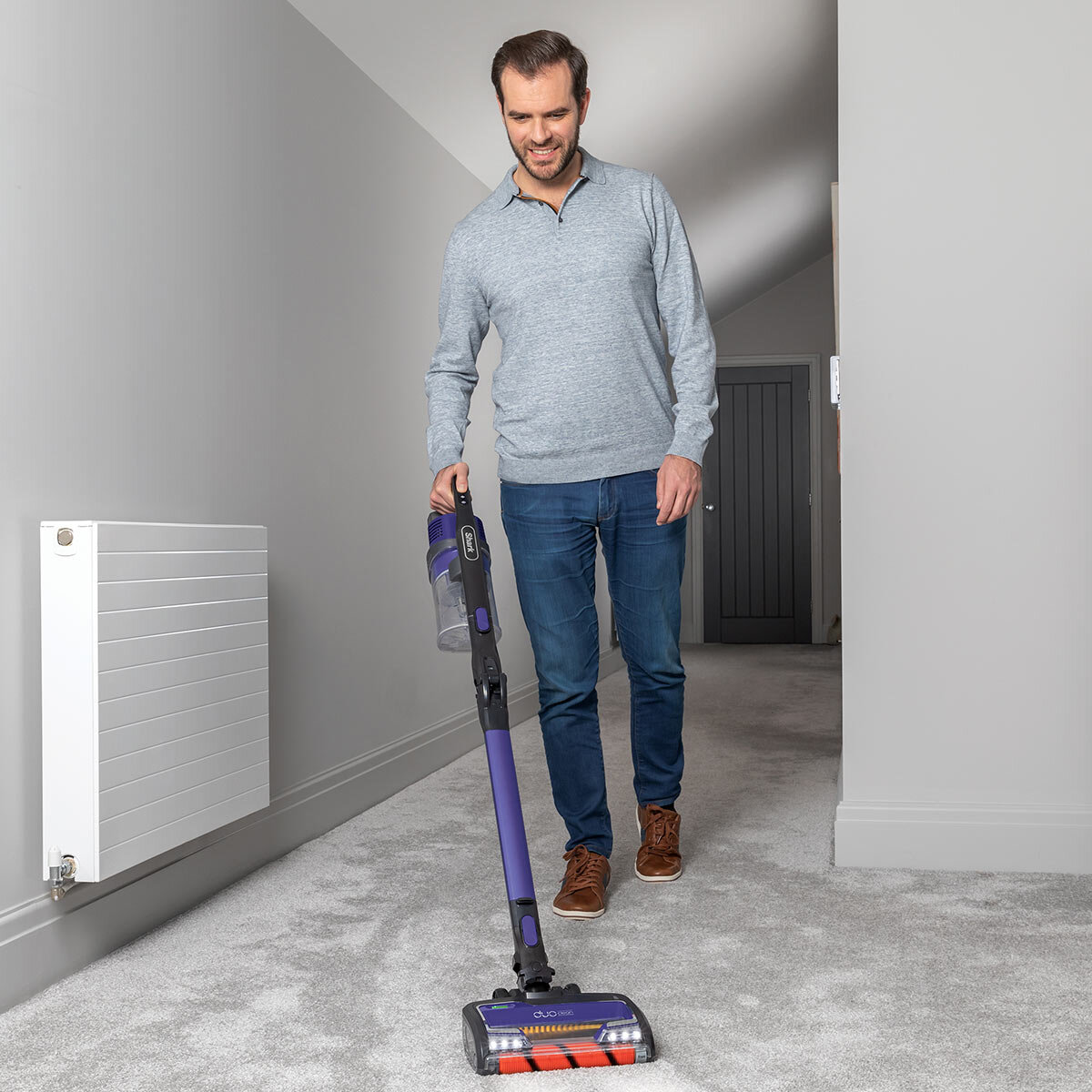 lifestyle image of man using vacuum on carpet