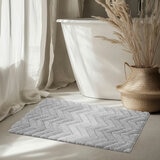 Textured bath mat placed in front of white bathtu