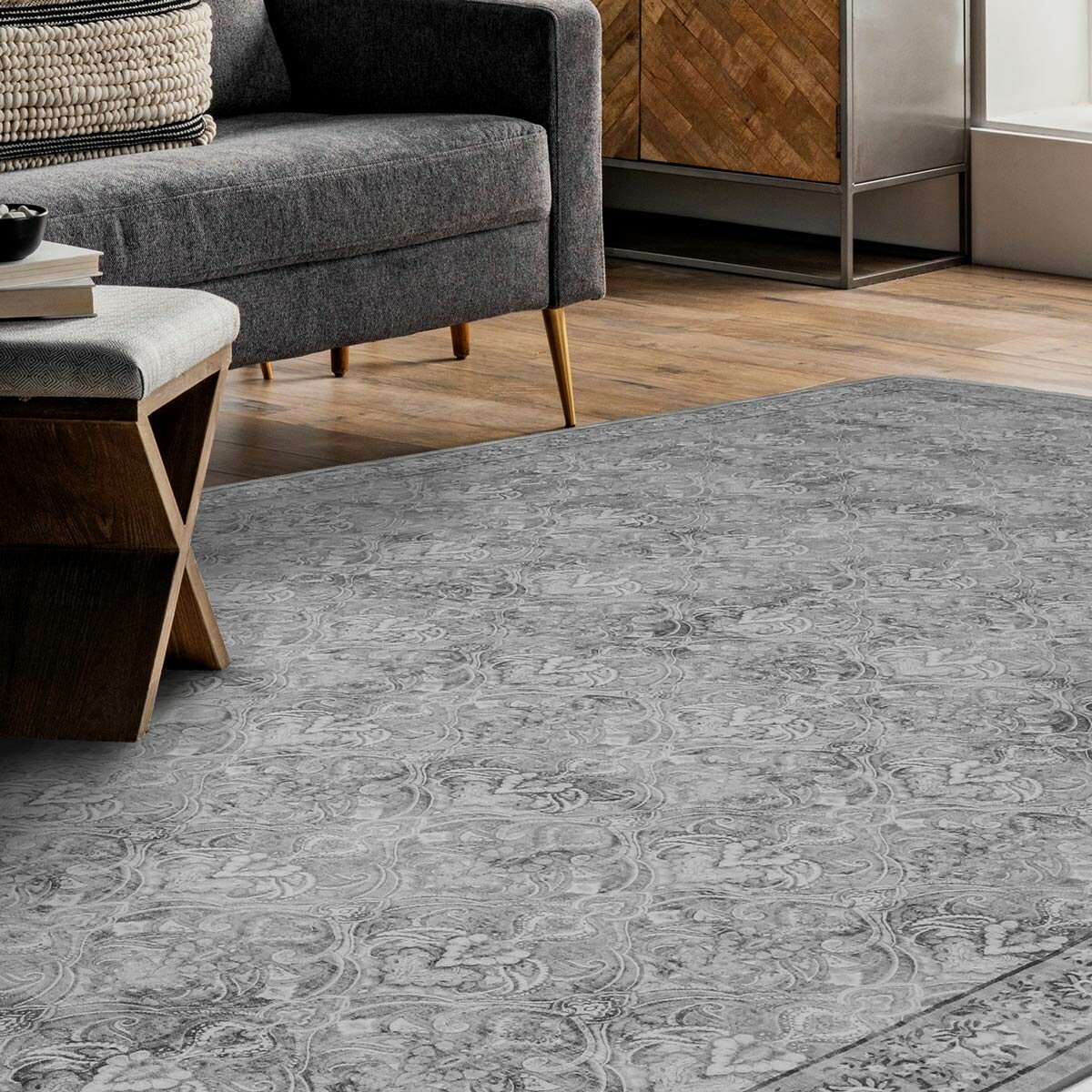 Grey patterned rug with floral and paisley design, styled in a modern living room with wooden furniture.