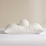 White pillow, showcasing firmness and softeness with a white balll placed on top