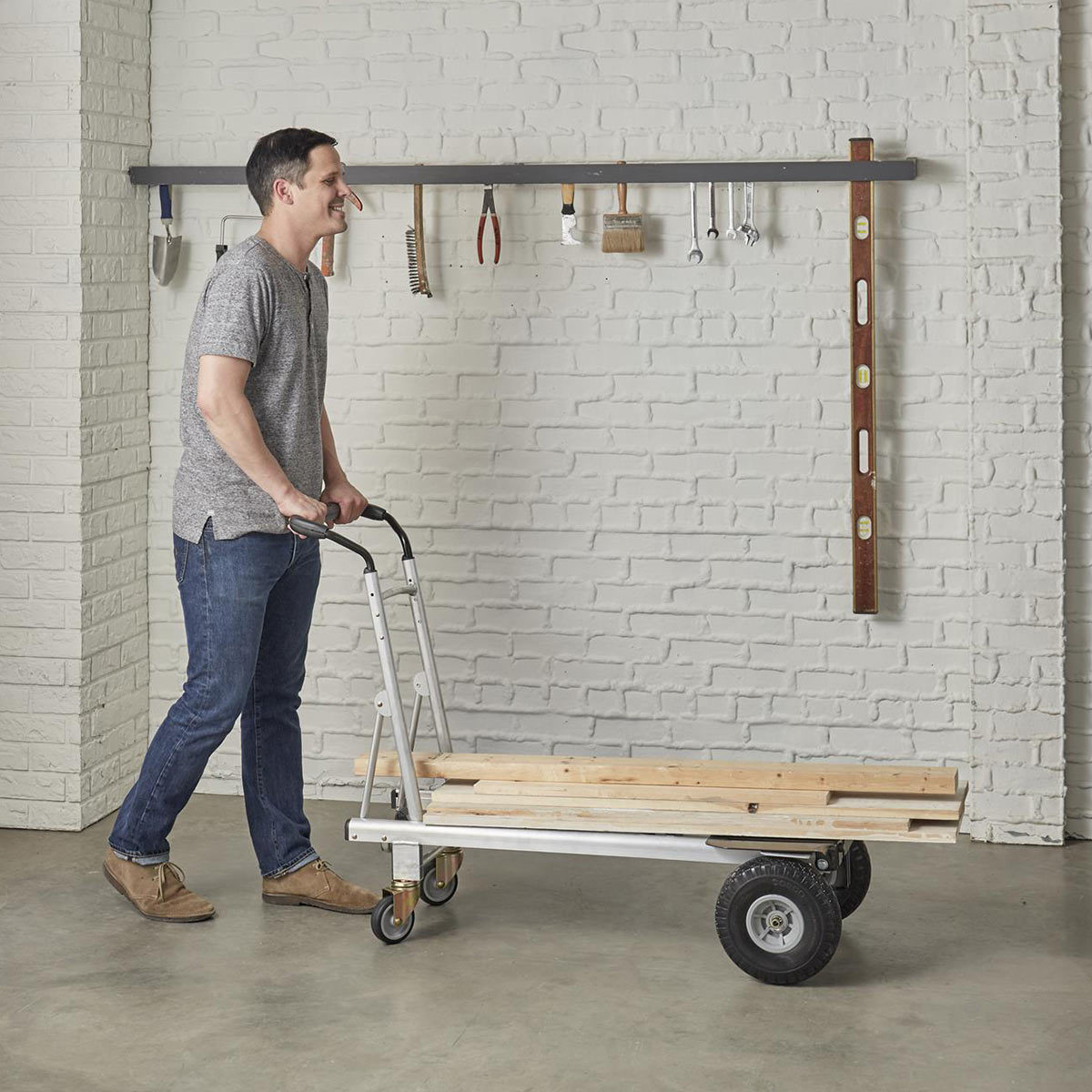 Man pushing hand truck loaded with planks of wood