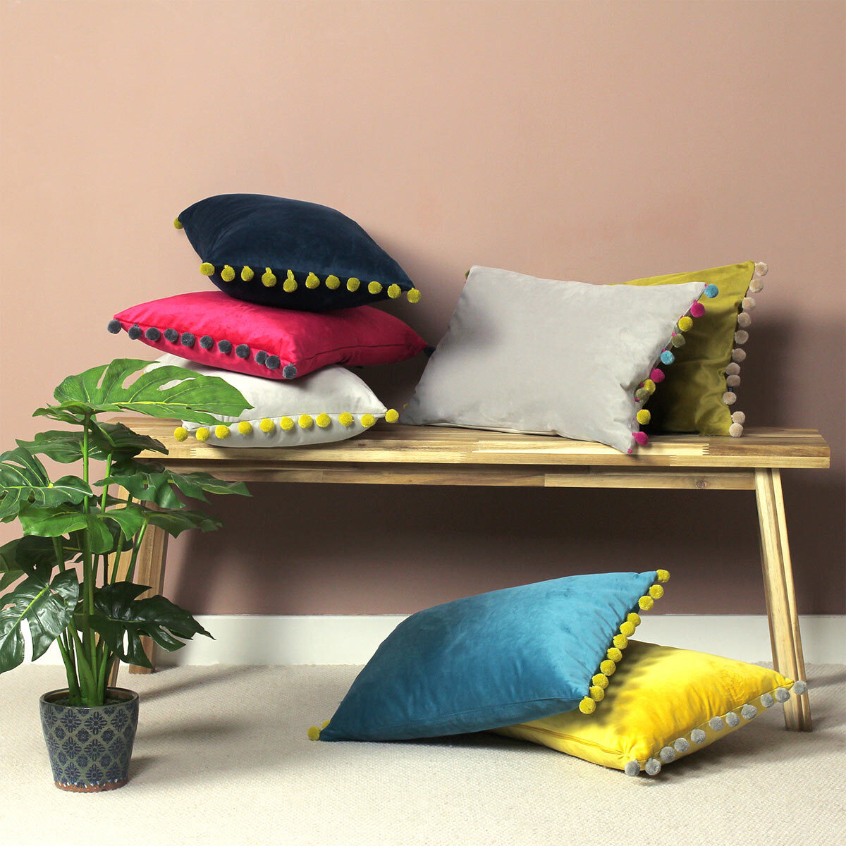 Lifestyle Image of Carnival Velvet Bolster Cushion with all colours