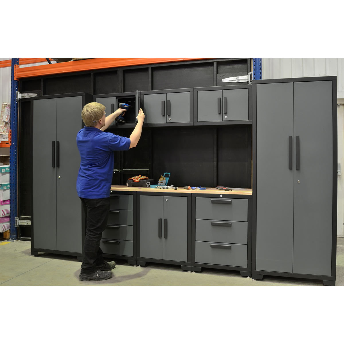 Tool storage cabinets in a warehouse with a man opening a door draw to put tool in
