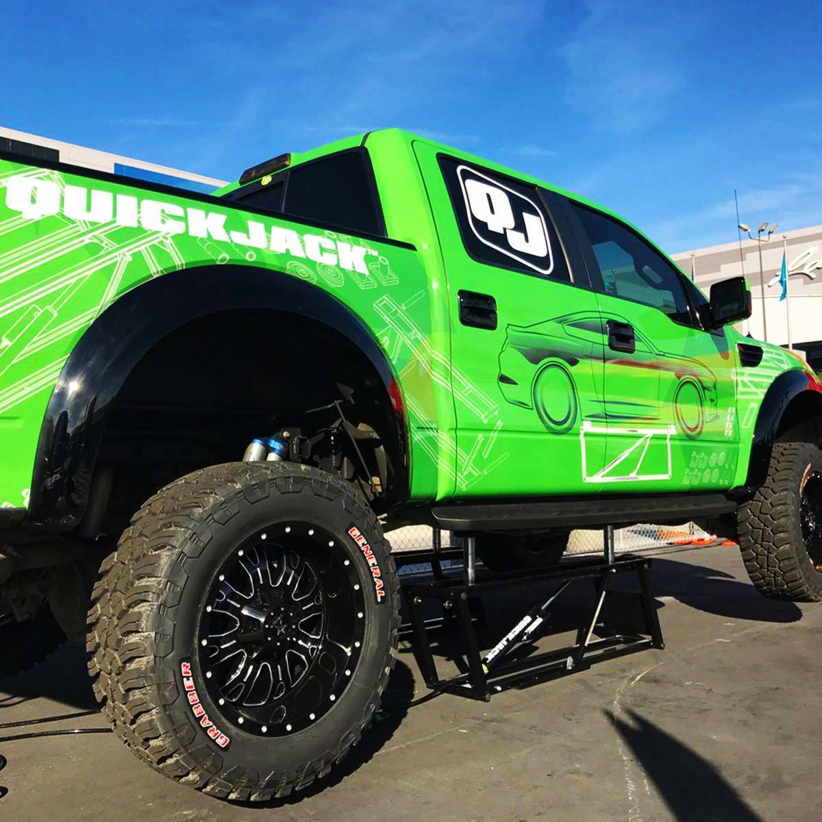 Image of green pickup with QuickJack logo lifted outside