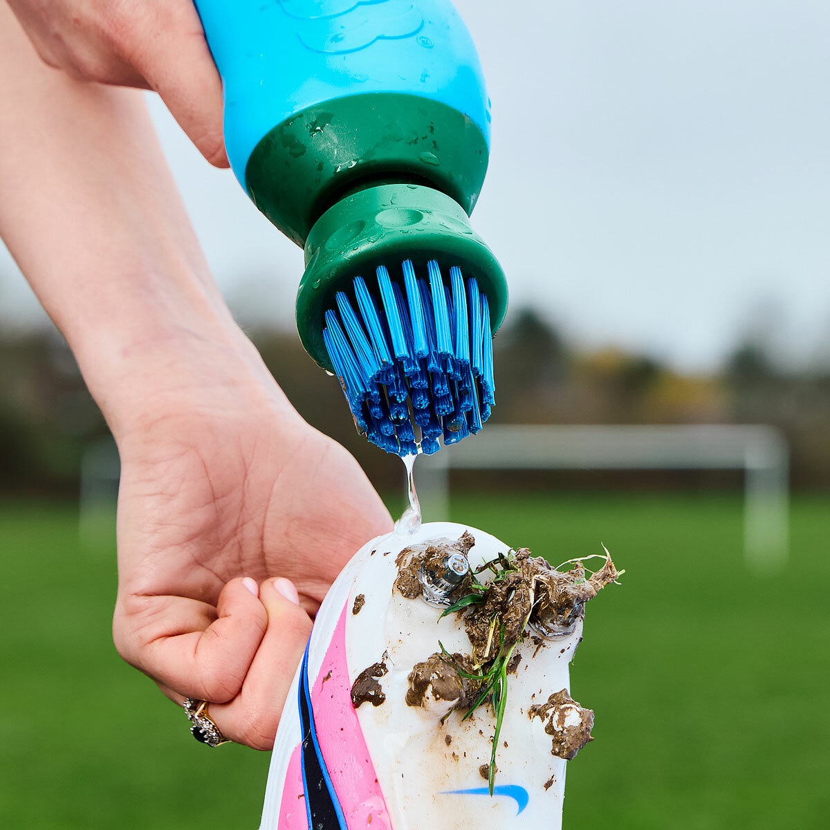 Lifestyle image of someone spraying water from the boot buddy onto a shoe