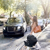 Lifestyle image of a woman, stopping a taxi while holing the carrier car seat