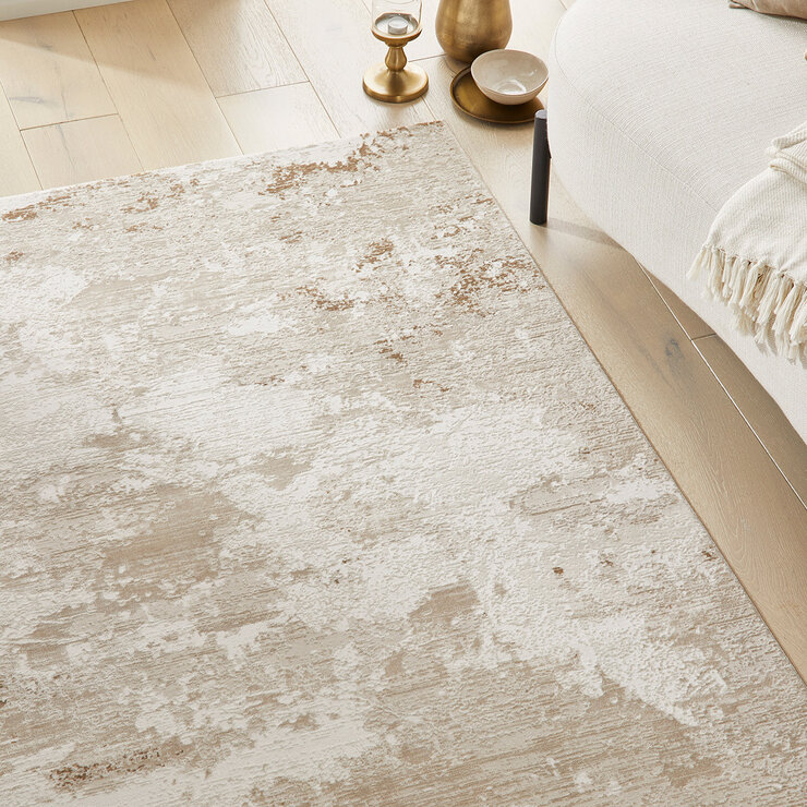 Neutral-toned rug with a soft abstract design in beige and cream, styled with a white sofa and gold side table on light wood flooring.