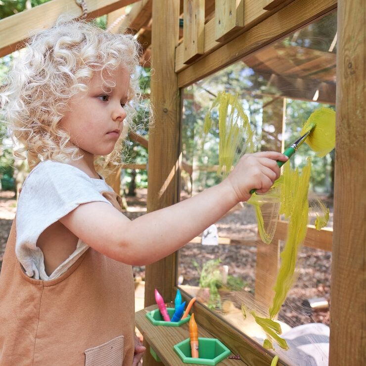 Lifestyle image of a child painting on a window