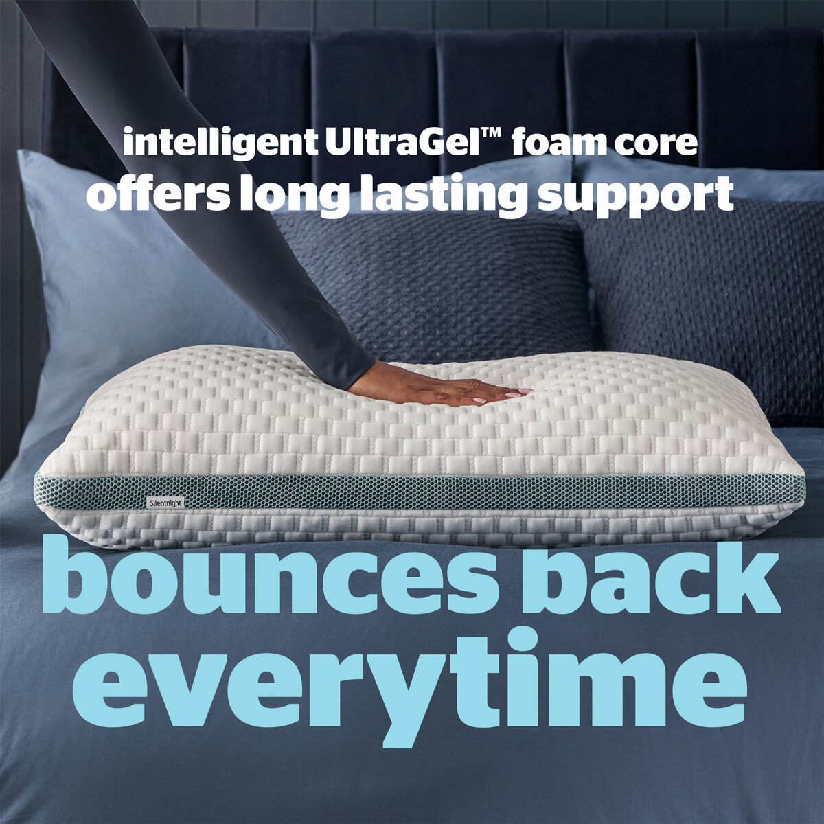 Hand pressing Silentnight UltraGel pillow on blue bed, showing foam core that offers lasting support and bounces back.