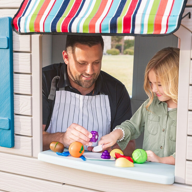 Lifestyle image of a child and adult playing with the pretend food at the window of the playhouse