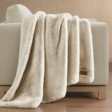 Beige faux fur throw with plush texture draped over a light sofa arm