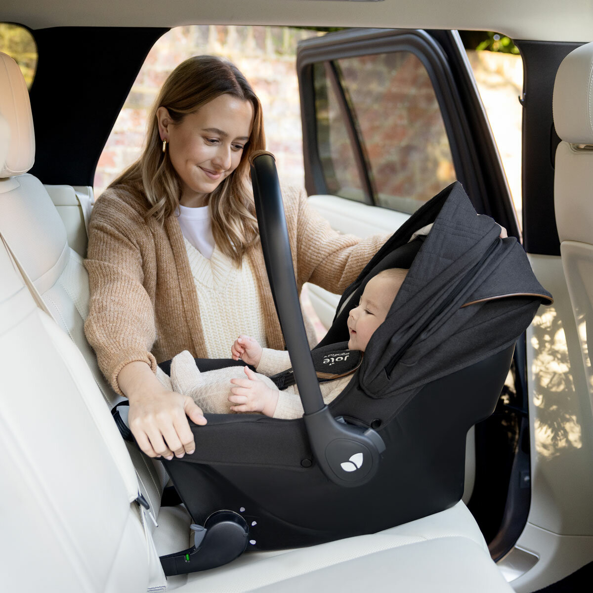 Lifestyle image of a woman putting the car seat into the car
