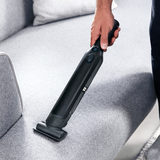 Image of hand held vacuum being used to clean the sofa